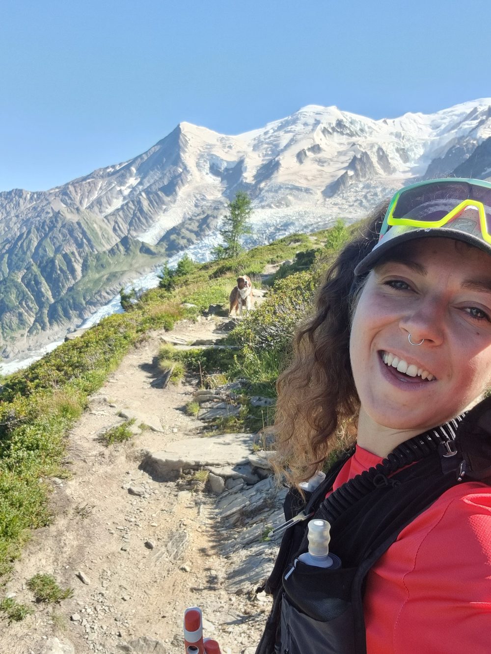 Lydie souriante sur un sentier, face aux sommets enneigés