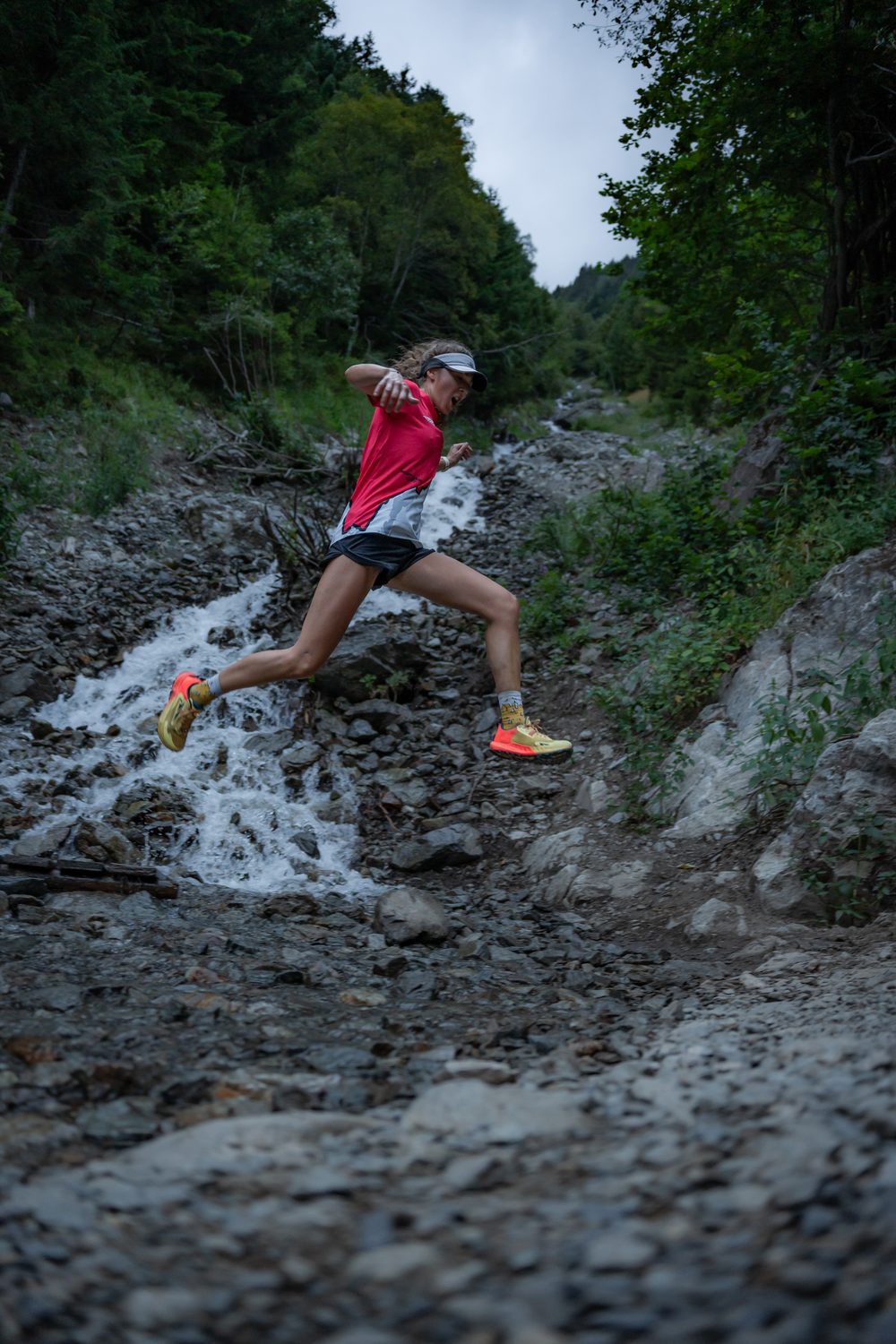 Lydie en plein saut sur un sentier de trail rocheux